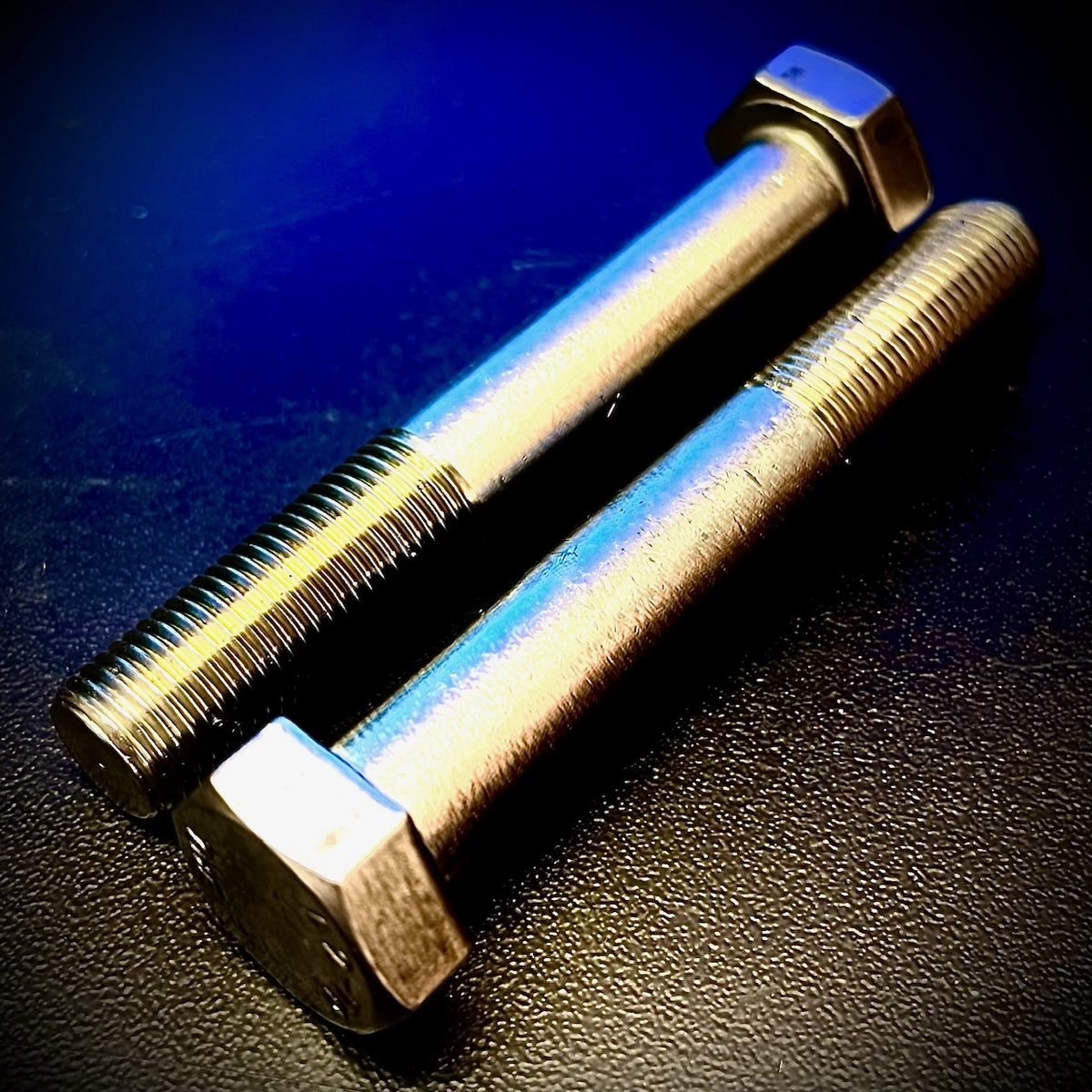 Two metal bolts on a dark textured surface