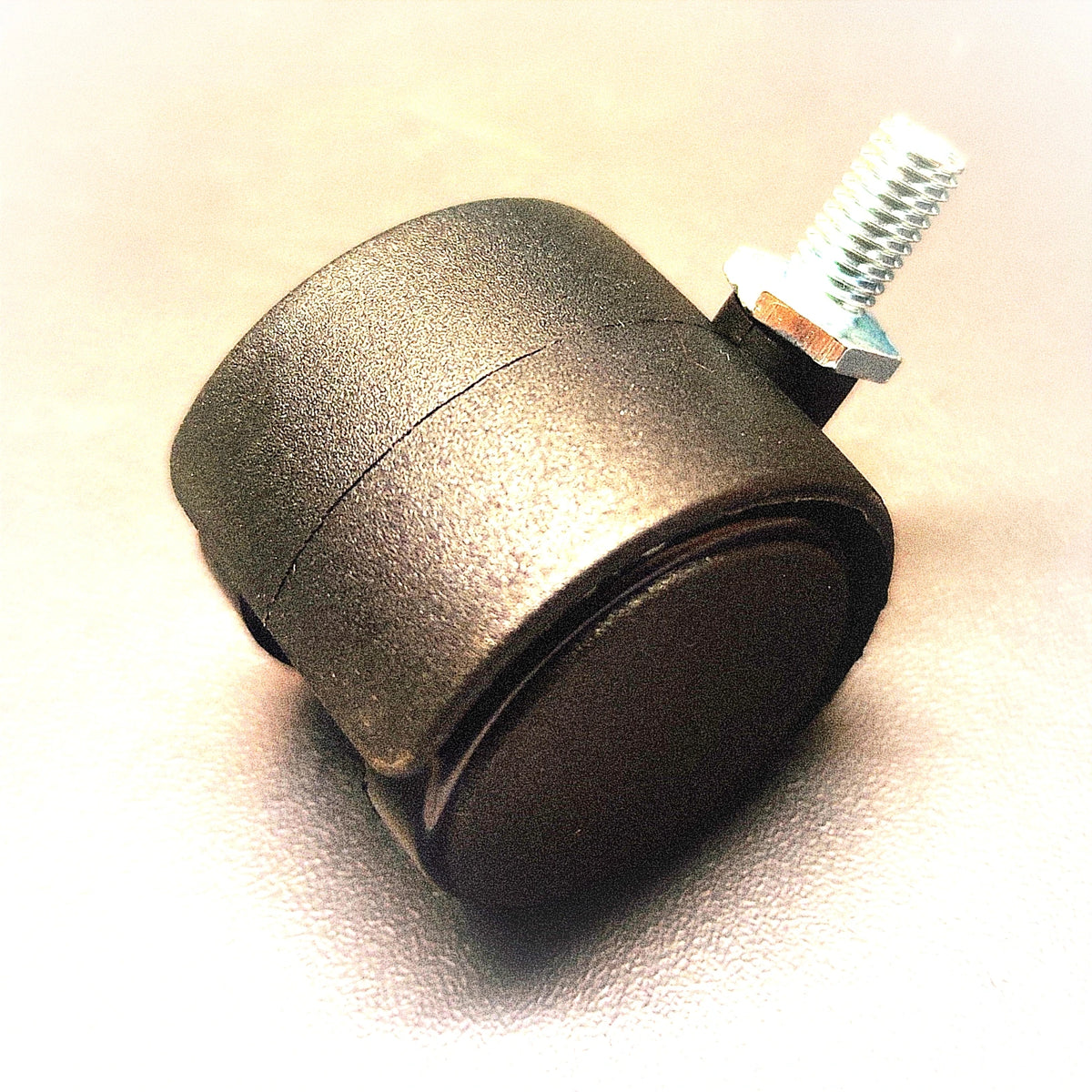Metal caster wheel with a screw on a beige background